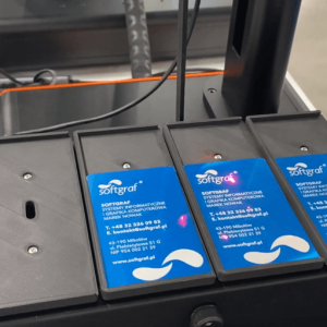 Karty znamionowe ułożone na podajniku grawerowane przez laser fiber